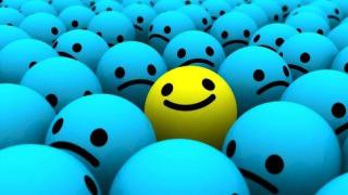 Visage souriant et positif seul au milieu de visages tristes